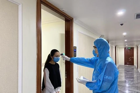 Cán bộ y tế của thành phố Hạ Long kiểm tra thân nhiệt cho khách cách ly y tế tại khách sạn Thái Sơn. (Nguồn: Báo Quảng Ninh)