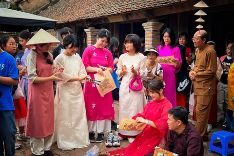 Du khách Hàn Quốc trải nghiệm làm tranh Đông Hồ ở Hà Nội. (Ảnh: Mai Mai/Vietnam+)