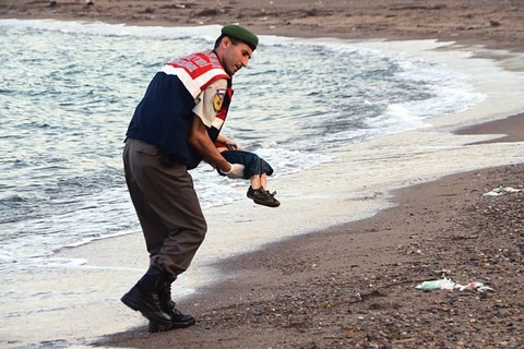 Người lính biên phòng Thổ Nhĩ Kỳ nâng xác cậu bé di cư Syria trôi dạt vào bờ biển ở một resort. (Nguồn: Telegraph)