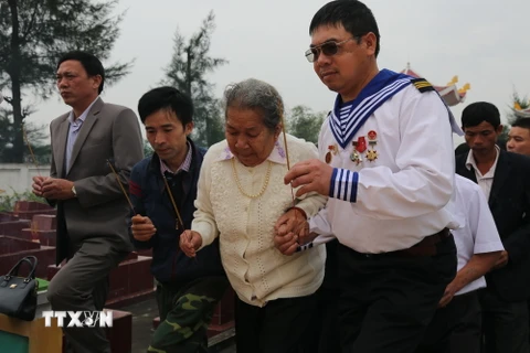 Mẹ của liệt sỹ Trần Văn Phương cùng các cựu binh, đồng đội, người thân thắp hương tưởng niệm anh hùng, liệt sỹ hy sinh trong trận chiến Gạc Ma. (Ảnh: Mạnh Thành/TTXVN)