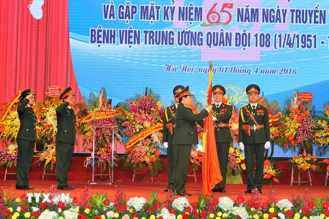 Đại tướng Ngô Xuân Lịch gắn Huân chương Bảo vệ Tổ quốc hạng Nhất lên Cờ truyền thống của Bệnh viện 108. (Ảnh: Trọng Đức/TTXVN)