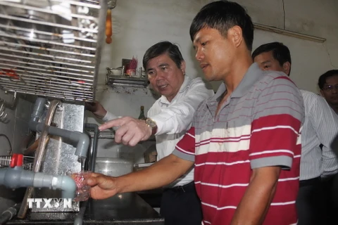 Chủ tịch UBND Thành phố Hồ Chí Minh Nguyễn Thành Phong kiểm tra việc thực hiện cung cấp nước sạch bằng thiết bị lọc nước tại hộ gia đình ông Lê Vũ Hồng ở ấp Bến Mương, xã An Nhơn Tây. (Ảnh: Thanh Vũ/TTXVN)
