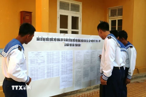 Các chiến sỹ trẻ, những người lần đầu tiên được tham gia bầu cử, xem bảng niêm yết danh sách cử tri. (Ảnh: Hứa Chung/TTXVN)