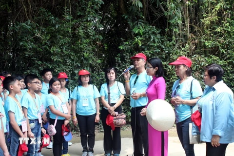 Đoàn giáo viên, học sinh kiều bào tỉnh Nakhon Phanom nghe hướng dẫn viên của Khu di tích Kim Liên kể về cuộc đời, sự nghiệp của Chủ tịch Hồ Chí Minh. (Ảnh: Bích Huệ/TTXVN) 