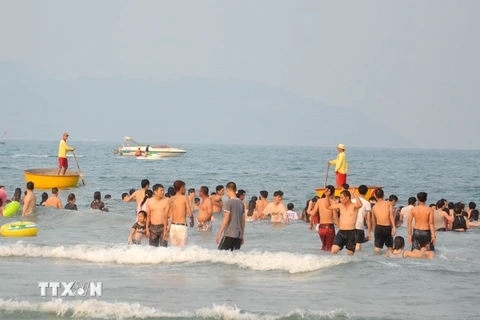 Đội viên của đội cứu hộ túc trực bằng thuyền thúng trên biển để đảm bảo an toàn cho người dân và du khách tắm biển Đà Nẵng. (Ảnh: Đinh Văn Nhiều/TTXVN) 