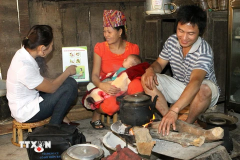 Nhân viên y tế thôn bản hướng dẫn bà mẹ chăm sóc sơ sinh tại xã Cà Tạ, huyện miền núi Kỳ Sơn, Nghệ An. (Ảnh: Dương Ngọc/TTXVN)