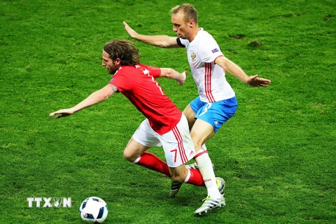  Pha tranh bóng giữa Joe Allen (trái) của Xứ Wales và cầu thủ Denis Glushakov (phải), đội Nga trong trận đấu. (Nguồn: AFP/TTXVN)