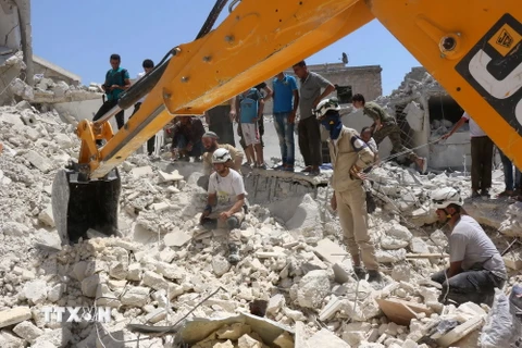 Tìm kiếm người sống sót dưới những đống đổ nát sau vụ không kích tại Karm Homad, phía bắc Aleppo. (Nguồn: AFP/TTXVN)