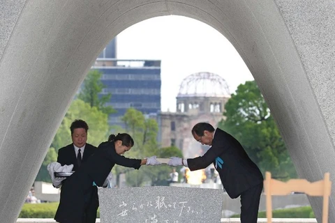 Thị trưởng Hiroshima Kazumi Matsui (phải) trao danh sách những nạn nhân bom nguyên tử cho một nạn nhân tại Công viên tưởng niệm Hòa bình. (Nguồn: AFP)