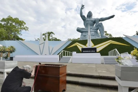 Một người phụ nữ quỳ trước bức tượng hòa bình trong Công viên Hòa bình ở thành phố Nagasaki. (Nguồn: Kyodo)