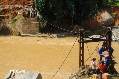 Hàng tiếp tế được vận chuyển bằng cáp treo qua chiếc cầu đã bị sập đến hai thôn Sủng Hoảng 1, Sủng Hoảng 2. (Ảnh: Hương Thu/TTXVN) 
