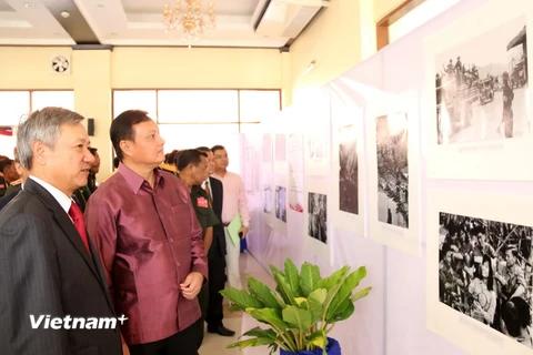 Đại sứ Nguyễn Mạnh Hùng và Bí thư, Tỉnh trưởng Savannakhet, ông Santiphap Phomvihane cùng các quan khách đang đi xem ảnh trưng bày tại triển lãm. (Ảnh: Phạm Kiên/Vietnam+)