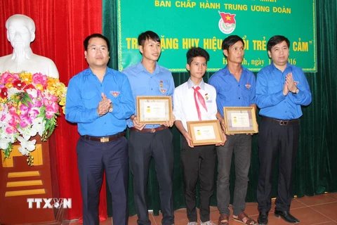 Trao tặng Huy hiệu 'Tuổi trẻ dũng cảm' cho 3 đoàn viên thanh niên là Võ Phong (34 tuổi), Võ Huân (28 tuổi) và em Đặng Quốc Vinh (13 tuổi) đã dũng cảm cứu người trong mưa lũ. (Ảnh: Hoàng Ngà/TTXVN)