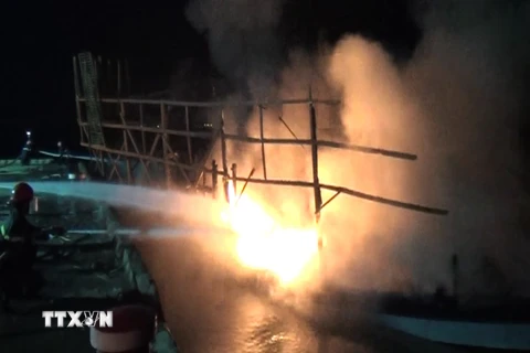 Cảnh sát phòng cháy chữa cháy tỉnh Quảng Nam nỗ lực phun nước dập tắt đám cháy trên tàu câu mực. (Ảnh: Đoàn Hữu Trung/TTXVN)