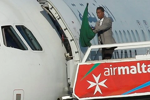 Một trong hai tên không tặc cầm lá cờ ở bên ngoài máy bay. (Nguồn: Reuters)