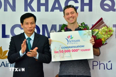 Bộ trưởng Bộ Văn hóa-Thể thao và Du lịch Nguyễn Ngọc Thiện tặng hoa, kỷ niệm chương cho ông Michael Tonge - du khách thứ 10 triệu đến Việt Nam trong năm 2016. (Nguồn: TTXVN)