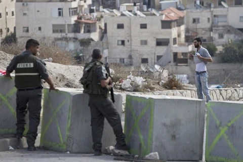 Cảnh sát Israel bắt một người Palestine vạch áo lên để kiểm tra. (Nguồn: AP)
