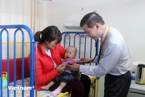 Bác sỹ Pau Kieu Kong đang thăm khám cho bệnh nhi. (Ảnh: Hoàng Nhương/Vietnam+)