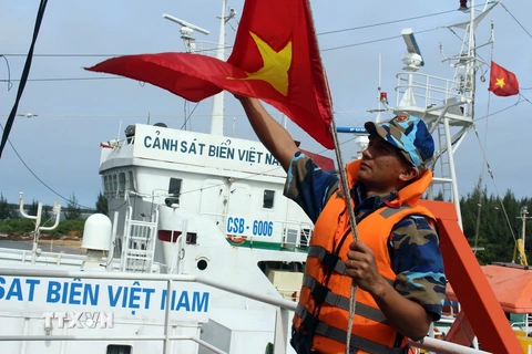 Chiến sỹ tàu Cảnh sát biển 9002 kéo cờ Tổ quốc, chuẩn bị xuất phát đi làm nhiệm vụ. (Ảnh: Đỗ Trưởng/TTXVN)