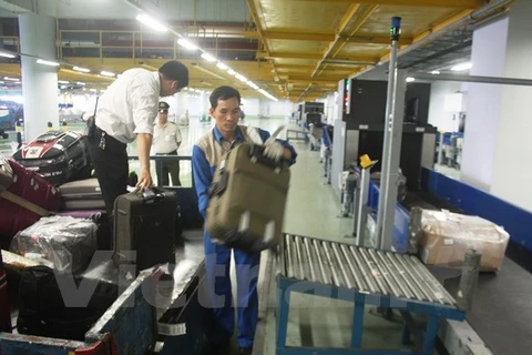 Hành lý được nhân viên bốc dỡ từ máy bay xuống xe để vận chuyển vào đảo hành lý trả cho khách. (Ảnh: Việt Hùng/Vietnam+)
