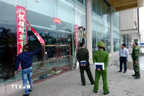 Lực lượng chức năng thành phố Móng Cái tháo dỡ biển kinh doanh của điểm mua sắm ASEAN vì vi phạm quy định trong hoạt động thương mại. (Ảnh: Văn Đức/TTXVN)