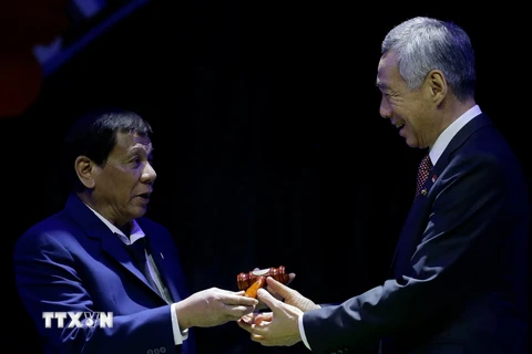Thủ tướng Singapore Lý Hiển Long (phải) nhận biểu tượng tại lễ chuyển giao chức Chủ tịch luân phiên ASEAN từ Tổng thống Philippines Rodrigo Duterte ở Manila ngày 14/11. (Nguồn: AFP/TTXVN)