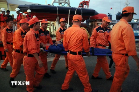 Lực lượng cứu hộ đưa ngư dân bị nạn lên bờ cấp cứu. (Ảnh: Đoàn Mạnh Dương/TTXVN)