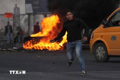 Người biểu tình Palestine ném đá vào binh sỹ Israel tại thành phố Nablus, khu Bờ Tây ngày 10/12. (Nguồn: THX/TTXVN)