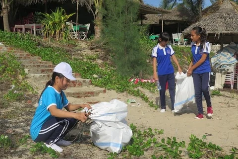 Các em học sinh tham gia nhặt rác tại bãi biển. (Ảnh: Nguyễn Sơn/Vietnam+)