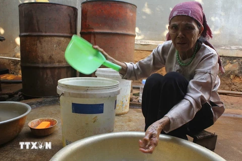 Bà Khuất Thị Sửu vẫn sử dụng nguồn nước này sinh hoạt hàng ngày dù biết nước có biểu hiện bất thường. (Ảnh: Phạm Cường/TTXVN)