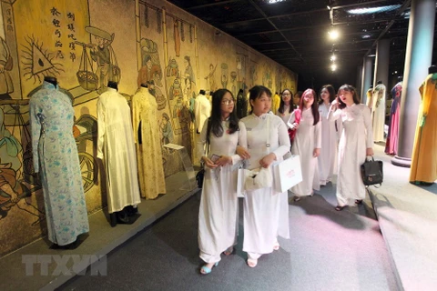Các em học sinh xem các mẫu áo dài tại triển lãm 'Duyên dáng Áo dài Thành phố Hồ Chí Minh.' (Ảnh: Quang Nhựt/TTXVN)