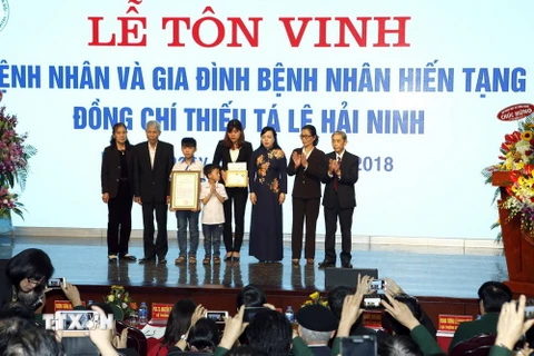 Bộ trưởng Bộ Y tế Nguyễn Thị Kim Tiến trao Kỷ niệm chương cho gia đình bệnh nhân Lê Hải Ninh. (Ảnh: Dương Ngọc/TTXVN)