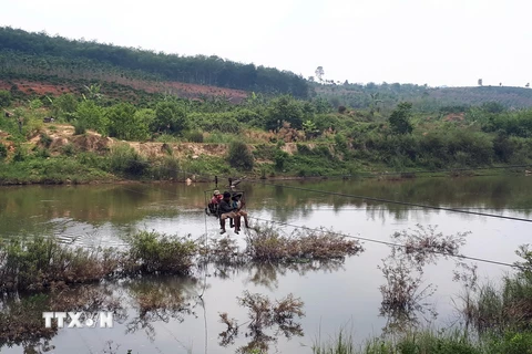 Người dân tại huyện Ngọc Hồi vượt sông bằng đu dây. (Ảnh: Quang Thái/TTXVN)