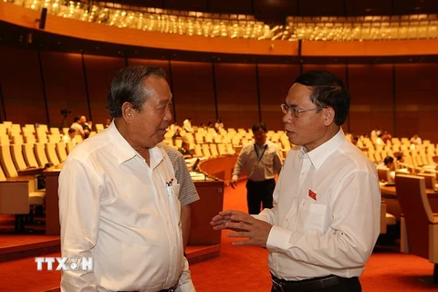 Phó Thủ tướng thường trực Chính phủ Trương Hòa Bình (bên trái) trao đổi với đại biểu Quốc hội bên lề phiên họp. (Ảnh: Dương Giang/TTXVN)