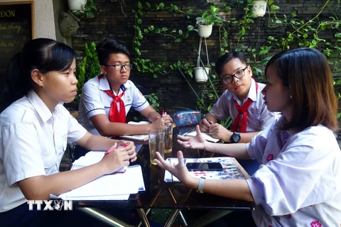 Nhóm phóng viên "nhí" (từ trái qua phải) Mai Hải Yến, Nguyễn Đức Kiệt, Trương Văn Hoài Khanh trao đổi với chị Lê Thị Tường Vi về đề tài bài viết. (Ảnh: Gia Thuận/TTXVN)
