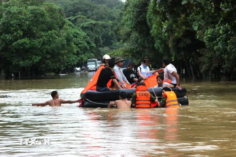 Cán bộ, chiến sỹ Công an Hà Giang hỗ trợ nhân dân qua vùng lũ an toàn. (Ảnh: Minh Tâm/TTXVN)