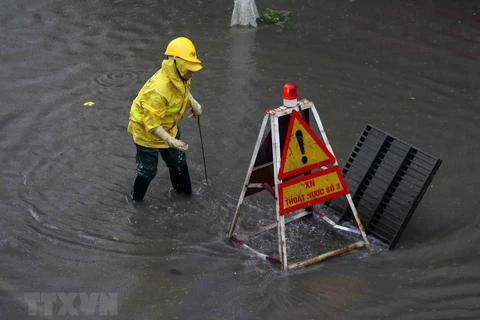 Công nhân Công ty thoát nước Hà Nội túc trực, cảnh báo người đi đường tại các điểm ngập nguy hiểm. (Ảnh: Thanh Tùng/TTXVN)