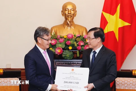 Thứ trưởng Bộ Ngoại giao Lê Hoài Trung (bên phải) trao tượng trưng số tiền Chính phủ Việt Nam hỗ trợ Chính phủ, nhân dân Lào khắc phục hậu quả sự cố vỡ đập thủy điện ở tỉnh Attapeu. (Ảnh: Lâm Khánh/TTXVN)