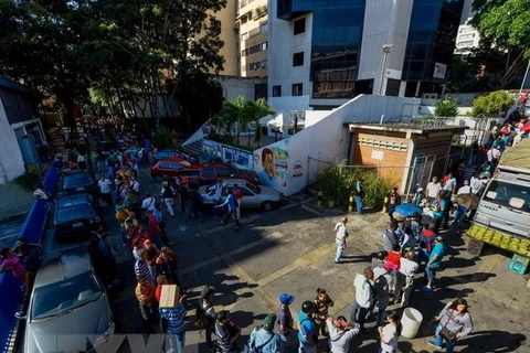 Người dân Venezuela xếp hàng chờ đổi tiền bên ngoài ngân hàng trung ương ở Caracas. (Nguồn: AFP/TTXVN)