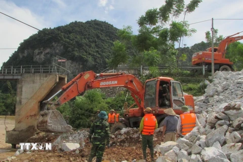 Ủy ban Nhân dân huyện Con Cuông huy động phương tiện, lực lượng khẩn cấp cứu cây cầu. (Ảnh: TTXVN)