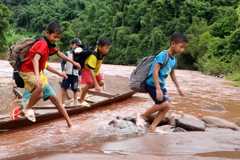 Học sinh phải đi thuyền vượt qua 2 con suối chảy xiết tới trường dự Lễ khai giảng năm học mới. (Ảnh: Việt Hoàng/TTXVN)