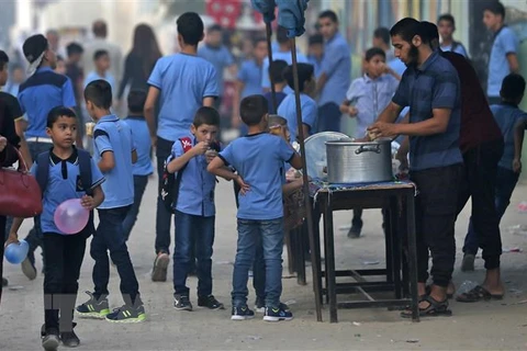Phát nước uống cho học sinh của một trường học do Cơ quan Liên hợp quốc vì người tị nạn Palestine (UNRWA) quản lý tại Dải Gaza ngày 29/8. (Ảnh: AFP/TTXVN)