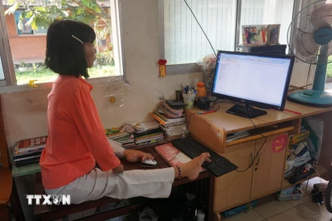 Chị Huỳnh Thị Xậm đang thực hiện công việc ghi chép, nhập dữ liệu tại thư viện của Trung tâm. (Ảnh: Thu Hoài/TTXVN)