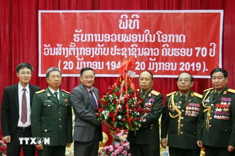 Đại sứ Nguyễn Bá Hùng (trái) trao hoa chúc mừng 70 năm Ngày thành lập Quân đội nhân dân Lào. (Ảnh: Xuân Tú/TTXVN)