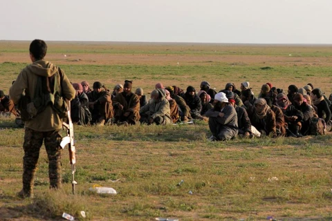 Một thành viên của Lực lượng Dân chủ Syria (SDF) giám sát những người dân ở làng Baghouz, tỉnh Deir Al Zor, Syria, ngày 22/2/2019. (Nguồn: Reuters)