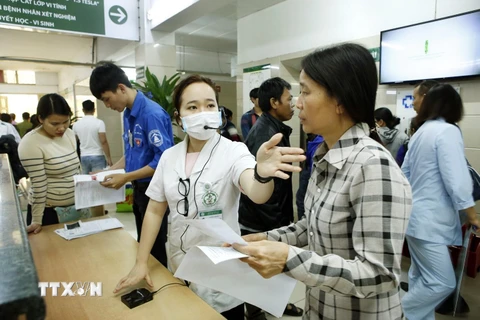 Nhân viên công tác xã hội hướng dẫn người bệnh làm thủ tục khám chữa bệnh tại bệnh viện Bạch Mai. (Ảnh: Dương Ngọc/TTXVN)