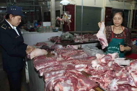 Nhân viên Thú y kiểm tra sản phẩm thịt lợn tại hộ kinh doanh trong chợ. (Ảnh: Vũ Sinh/TTXVN)