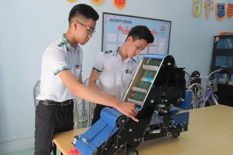 Nguyễn Hữu Thực và Trần Hoàng Nguyên với mô hình máy điều khiển tự động thu gom nông sản. (Ảnh: Nguyễn Thành/TTXVN)
