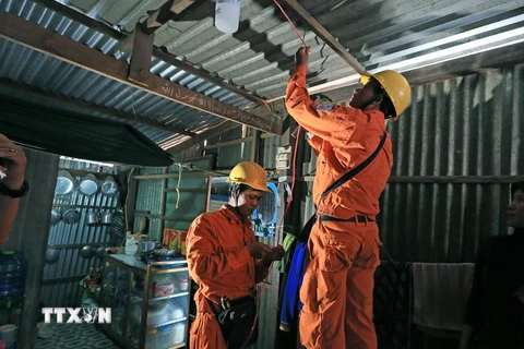 Công nhân Điện lực Châu Đốc (Công ty Điện lực An Giang) sửa chữa và lắp bóng tiết kiệm điện miễn phí cho các hộ nghèo đồng bào dân tộc trên địa bàn huyện Châu Đốc. (Ảnh: Ngọc Hà/TTXVN)