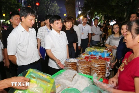 Ông Ngô Văn Quý, Phó Chủ tịch Ủy ban Nhân dân thành phố Hà Nội cùng các đại biểu tham quân các gian hàng ẩm thực. (Ảnh: Thành Đạt/TTXVN)